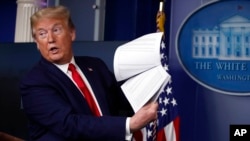 ARCHIVO - El presidente Donald Trump sostiene papeles mientras habla sobre el coronavirus en la sala de conferencias de prensa James Brady de la Casa Blanca el 20 de abril de 2020 en Washington.