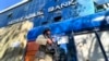 Anggota pasukan Taliban berjaga di luar sebuah bank di Kabul, Afghanistan, pada 13 Februari 2022. (Foto: AP/Hussein Malla)