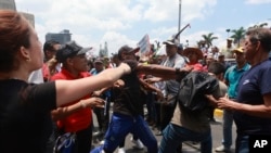 Un partidario del gobierno (centro) golpea a una persona que asiste a una marcha por el Día Internacional de los Trabajadores en Caracas, Venezuela, el miércoles 1 de mayo de 2024.