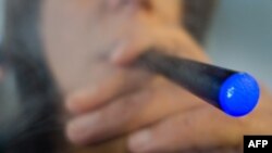 FILE- A woman smokes a "Blu" e-cigarette (electronical cigarette) in Washington, DC. The number of US youths who have tried e-cigarettes tripled from 2011 to 2013, raising concerns about the potential for a new generation of nicotine addicts, US health a