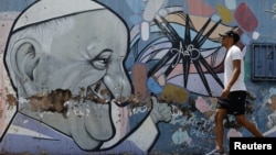 Un hombre pasa junto a un mural que representa al Papa Francisco, quien continúa hospitalizado. En Brasilia, Brasil, el 26 de febrero de 2025.