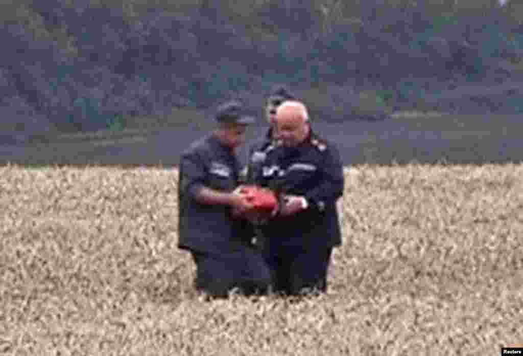 A rescue worker shows a flight data recorder to a colleague at the crash site of Malaysia Airlines Flight MH17 in Hrabove July 18, 2014 in this still image taken from video. Rescue workers have recovered a "black box" flight recorder from the wreckage of the Malaysian airliner.