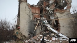 Un militaire ukrainien passe devant un bâtiment détruit sur la ligne de front avec les séparatistes soutenus par la Russie à Mariinka, dans la région de Donetsk, le 7 février 2022.