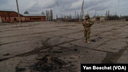 A Ukrainian soldier observes the place where a bomb fell, killing a fellow soldier not far from the front line in eastern Ukraine, Feb. 19, 2022, in Novoluganske, Ukraine. (Yan Boechat/VOA)