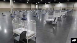 FILE - Cots and cribs are arranged at the Mountain America Expo Center in Sandy, Utah, on April 6, 2020, as an alternate care site or for hospital overflow amid the COVID-19 pandemic.