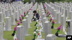 2019年6月6日，一名韩国妇女在韩国首尔的国家公墓，在韩战中牺牲的亲戚墓前祈祷。