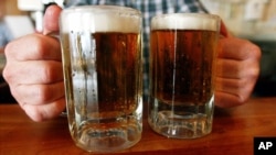 Arhiva- Barmen poslužuje dve krigle piva u taverni u Montpeliru, Vermont, 29. juna 2004.