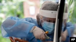 A health worker takes blood to perform an Enhanced Chemiluminescence Immunoassay (ECLIA) antibody test at a drive-thru COVID-19 testing facility at a hospital in metropolitan Manila, Philippines, July 8, 2020. 