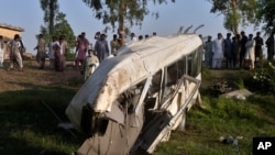 Penduduk setempat berkumpul di sekitar bus yang hancur akibat tabrakan dengan kereta api di Farooq Abad, distrik Sheikhupura, Pakistan, Jumat, 3 Juli 2020. 