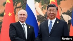 资料照片：2023 年10月18日，俄罗斯总统弗拉基米尔·普京在中国北京举行的“一带一路”论坛上与中国国家主席习近平握手。