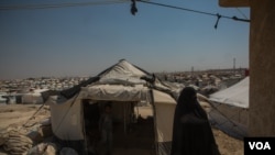 A woman walks among the thousands of tents at Al-Hol Camp. Here, the Islamic rules implemented by IS are still followed as they were under the group, Aug. 26, 2019. (Yan Boechat/VOA) 