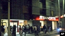 People stand on a sidewalk outside a building in Mexico City after an earthquake, December 10, 2011.