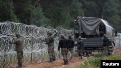 FILE - Polish soldiers build a fence on the border between Poland and Belarus near the village of Nomiki, Poland, August 26, 2021.