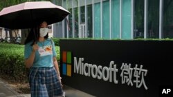 资料照片:一名戴口罩防新冠传染的女士走过微软公司北京一分枝机构。(2021年7月20日）