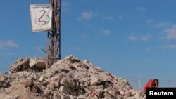 Una mujer se sienta sobre los escombros de lo que fue su casa el 17 de febrero de 2023, en la localidad siria de Jableh, devastada por el mortal terremoto que dejó miles de muertes en Turquía y Siria.