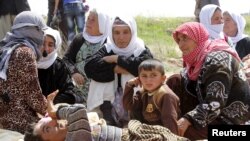 FILE - More than 200 Yazidi sect members, freed eight months after they were taken captive by Islamic State militants, wait on the edge of Kirkuk for relocation, April 8, 2015.