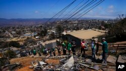 Aficionados del club de fútbol Wanders hacen labores voluntarias de limpieza en un área afectada por incendios forestales en el vecindario Villa Independencia, el martes 6 de febrero de 2024, en Viña del Mar, Chile.