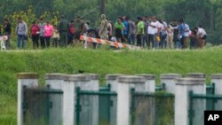 ARCHIVO: Migrantes hablan con funcionarios en un camino cerca del río Grande después de cruzar la frontera desde México a Texas el 11 de mayo de 2023.