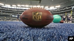 FILE - A football rests on the colored turf during an NFL football minicamp at the Dallas Cowboys' stadium, June 19, 2014, in Arlington, Texas.