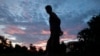 FILE - A Cambodian woman is silhouetted as she walks, on the outskirts of Phnom Penh, Cambodia.