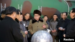 金正恩和科學家圍在一個小型銀色球體旁