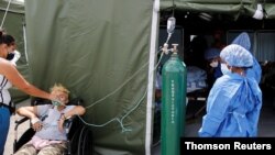 Un médico observa mientras monitorea la evolución de un paciente que padece COVID-19, en la carpa del hospital de campaña Poliedro de Caracas, el 21 de marzo de 2021..