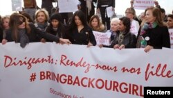 Mantan Ibu Negara Prancis Carla Bruni-Sarkozy (kiri) dan Valerie Trierweiler (kanan) bersama para politisi dan seniman membawa spanduk yang berbunyi, "Para Pemimpin, Pulangkan Anak Perempuan Kami", dalam demonstrasi di Paris mengutuk penculikan para siswi di Nigeria oleh Militan Boko Haram (13/5/2014). 