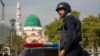 FILE - A Pakistani police officer stands guard outside the Barri Imam shrine in interior Sindh, Islamabad, Pakistan, Feb. 17, 2017.
