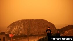 Orang-orang berjalan di tepi pantai Samudra Pasifik saat asap dari kebakaran hutan menutupi area di dekat Seal Rock, Oregon. (Foto: Reuters)
