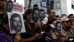 Les journalistes et les militants tiennent des images de photojournaliste tué Ruben Espinosa découpées lors d'une manifestation au monument de l'Indépendance à Angel de México, le dimanche 2 août 2015. 