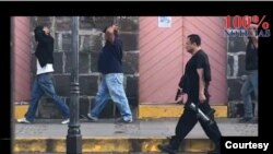 En una imagen del clausurado noticiero nicaragüense 100% Noticias, aparece el ahora sancionado comisionado policial, Ramón Avellán, custodiando con una pistola en la mano a varios manifestantes arrestados en 2018. Foto cortesía 100% Noticias.