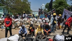Para pengunjuk rasa terlihat berkumpul di dekat barikade. Pasukan keamanan bertindak keras terhadap demonstrasi yang menentang kudeta militer, di Yangon, Myanmar, 20 Maret 2021. (Foto: AFP)