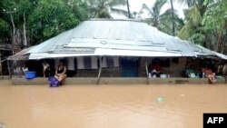 Des résidents se sont réfugiés sous le toit d'une maison dans le district de Paquite à Pemba après le passage du cyclone Kenneth dans le nord du Mozambique le 29 avril 2019.