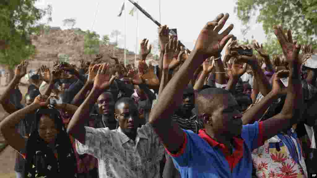Mains levées, des personnes déplacées suite aux attaques des combattants islamistes s’apprêtent à passer au point de contrôle de la sécurité avant de voter, à Yola, au Nigeria, samedi 28 mars 2015.