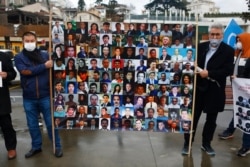 FILE - Members of the Uighur community living in Turkey hold a placard with pictures of Uighurs they say they fear are being kept in detention camps in China, during a protest near China's consulate in Istanbul, Feb. 10, 2021.