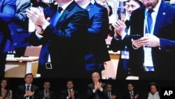 歷經協議難產而延會，COP29主席穆赫塔爾·巴巴耶夫(中)在閉幕全體會議上率眾鼓掌。 (美聯社：2024年11月24日)