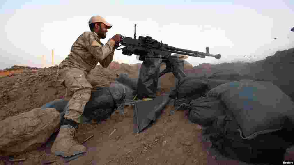 A member of the Kurdish Peshmerga force fires a dushka at Sulaiman Pek front line in the northwest of Tikrit city, Aug. 31, 2014.