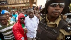 Le leader de l'opposition et candidat à la présidence Kizza Besigye, au centre, est arrêté par la police antiémeute après avoir tenté de marcher avec ses partisans le long d'une rue dans le centre de Kampala, en Ouganda, 15 février 2016.