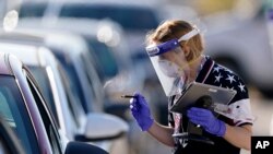 Una funcionaria electoral da instrucciones a un conductor en un punto de votación en Kansas City, Kansas, el 3 de noviembre de 2020.
