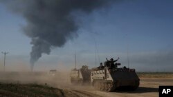 ARCHIVO - Soldados israelíes se mueven en vehículos blindados de transporte de personal (APC) cerca de la frontera entre Israel y Gaza mientras el humo se eleva hacia el cielo en la Franja de Gaza, visto desde el sur de Israel el 21 de enero de 2024.