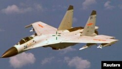 A Chinese J-11 fighter jet is seen flying near a U.S. Navy P-8 Poseidon about 215 km (135 miles) east of China's Hainan Island in this U.S. Department of Defense handout photo taken August 19, 2014. China on Saturday called US criticism of an approach by one of its jets to a US Navy patrol plane off the Chinese coast earlier this week "completely groundless" and said its pilot had maintained a safe distance from the US aircraft. Picture taken August 19, 2014. REUTERS/U.S. Navy/Handout 
