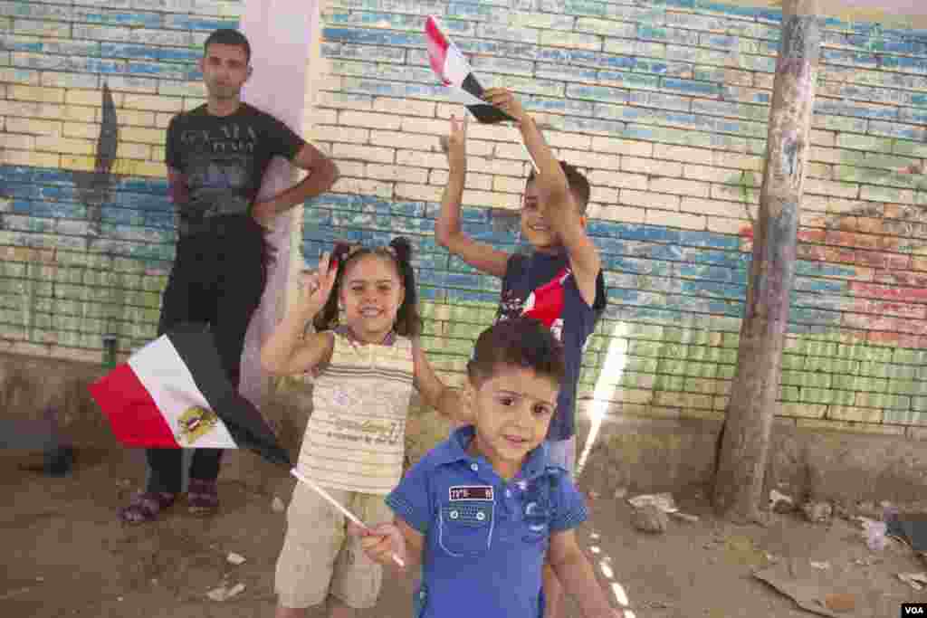 Anak-anak melambaikan bendera di luar TPS di Kairo, 27 Mei 2014. (Hamada Elrasam /VOA)