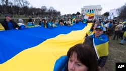 Los ucranianos y sus partidarios llevan una enorme bandera ucraniana durante una manifestación en el National Mall cerca del Monumento a Lincoln en Washington, conmemorando dos años desde la guerra. [Foto: Archivo/AP/Manuel Balce Ceneta]. 