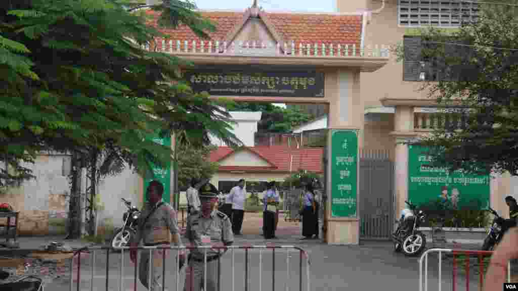 នគរបាលកំពុងឈររក្សាសន្តិសុខ ខណៈអនុរក្សកំពុងឈរចាំត្រួតពិនិត្យបេក្ខជនមុននឹងអនុញ្ញាតឱ្យចូលក្នុងមណ្ឌលប្រលងវិទ្យាល័យព្រះស៊ីសុវត្ថិ កាលពីថ្ងៃទី២៤ សីហា ឆ្នាំ២០១៥។ (ស៊ូ ពិសែន/VOA)