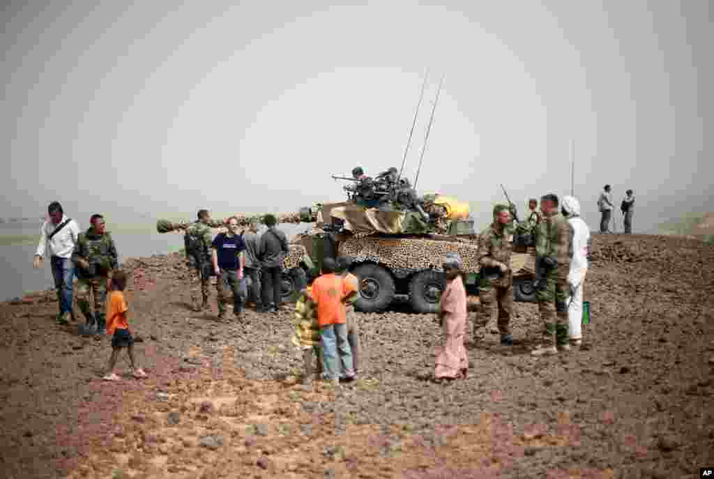 During an official visit organized by the French military, residents and journalists gather around a French Sagay tank positioned overlooking the bridge crossing the river Niger at the entrance of Gao, Mali, January 31, 2013.