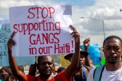 FILE - A protester holds up a sign during a protest to demand the resignation of Haiti's President Jovenel Moise, in Port-au-Prince, Haiti, Dec. 10, 2020.
