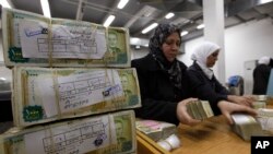 FILE - In this January 13, 2010 file photo, Syrian employees stack packets of Syrian currency in the Central Syrian Bank in, Damascus, Syria.