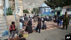 Varias personas se preparan para las oraciones del Eid al-Fitr, la festividad religiosa que marca el fin del Ramadán, afuera de una mezquita en Kabul. 