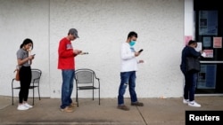 FILE - People who lost their jobs wait in line to file for unemployment at a Workforce Center in Fayetteville, Arkansas, April 6, 2020.