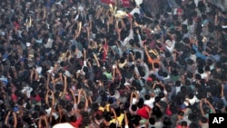 In this Thursday, March 5, 2015 photo, members of a mob raise their hands to take photos of a man, top center, accused of rape after he was lynched and hung in the city landmark Clock Tower in Dimapur, in the northeastern Indian state of Nagaland. 